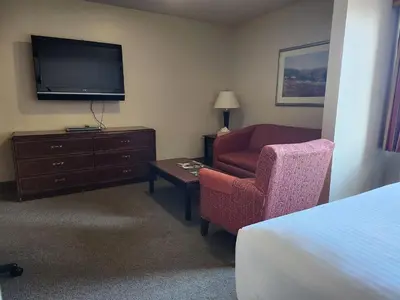 a hotel room with a bed and a chair and a television at Ashley Quarters Hotel Airport-Cincinnati in Florence