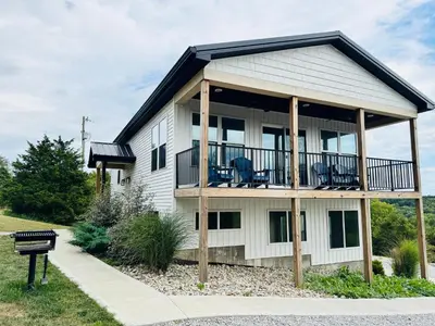 a house with a wrap around deck with chairs on it at 100 Acre Relaxing Retreat Near ARK- The Farmhouse in Williamstown