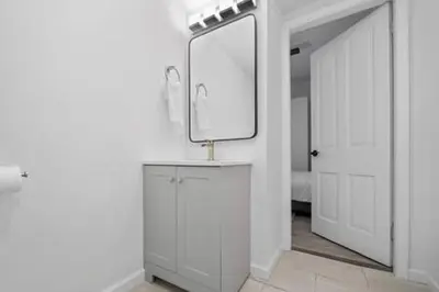a white bathroom with a mirror and a sink at Charming Mt. Adams 1BR - Near Downtown & Stadiums in Cincinnati