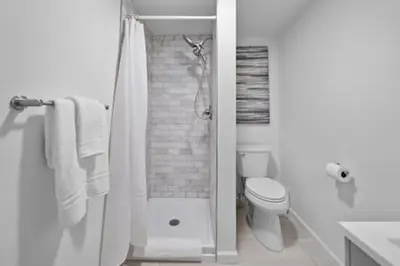 a white bathroom with a shower and a toilet at Charming Mt. Adams 1BR - Near Downtown & Stadiums in Cincinnati