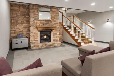 a living room with a fireplace and a staircase at Wingate Suites By Wyndham Mansfield Ontario in Mansfield