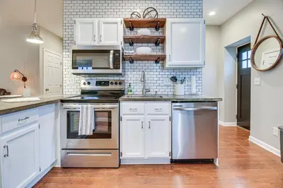 a kitchen with white cabinets and stainless steel appliances at Historic Loveland Apt Walk to Little Miami River! in Loveland
