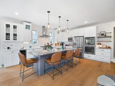 a kitchen with white cabinets and a blue island with chairs at The Emerald Manor in Cleveland