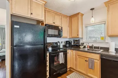 a kitchen with a black refrigerator and wooden cabinets at Newly Renovated Tremont Treasure I Cozy + Modern in Cleveland
