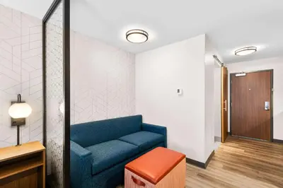 a waiting room with a blue couch and a stool at Everhome Suites Lexington - Horse Park in Lexington