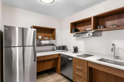 a kitchen with a stainless steel refrigerator and wooden cabinets at Everhome Suites Lexington - Horse Park in Lexington