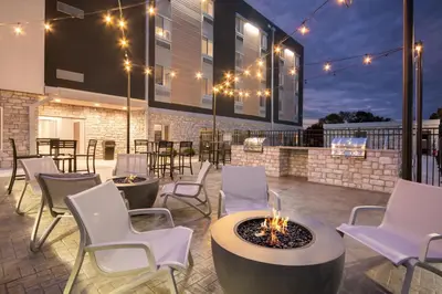 a patio with white chairs and tables and lights at Everhome Suites Lexington - Horse Park in Lexington