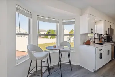 a kitchen with two stools and a small table in front of windows at Tranquil Pet Friendly Retreat residence in Reynoldsburg