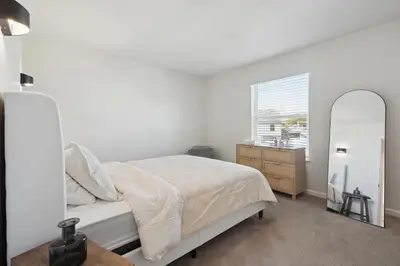 a white bedroom with a bed and a mirror at Tranquil Pet Friendly Retreat residence in Reynoldsburg