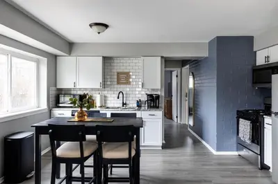 a kitchen with white cabinets and a black table and chairs at Westlake Elegance - Detroit Unit 3 in Westlake