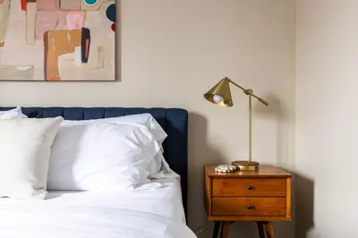 a bed with white sheets and a lamp on a night stand at Maple Heights Bliss - Unit 12 in Maple Heights