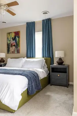 a bedroom with two beds and a window with blue curtains at Maple Heights Bliss - Unit 12 in Maple Heights