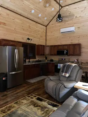 a kitchen with a couch and a stainless steel refrigerator at Lakeside Cabin Hot tub close to Ark Encounter in Corinth