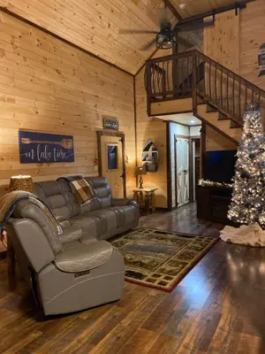 a living room with a couch and a christmas tree at Lakeside Cabin Hot tub close to Ark Encounter in Corinth