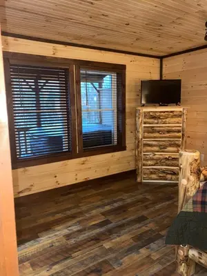a log cabin with a television and a window at Lakeside Cabin Hot tub close to Ark Encounter in Corinth