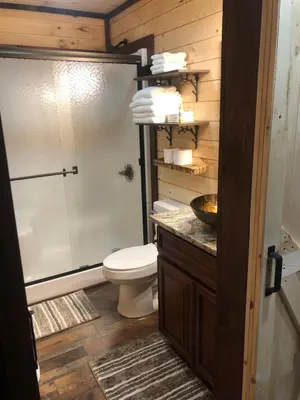 a bathroom with a toilet and a glass shower at Lakeside Cabin Hot tub close to Ark Encounter in Corinth