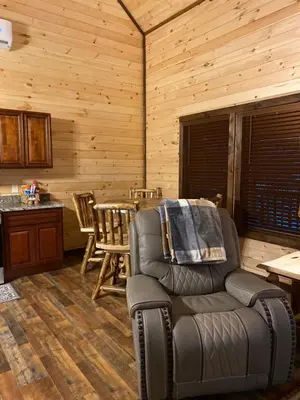 a living room with a leather chair and a table at Lakeside Cabin Hot tub close to Ark Encounter in Corinth
