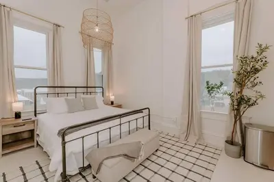 a white bedroom with a bed and two windows at East Main Lofts - Minimalist 302 in Madison