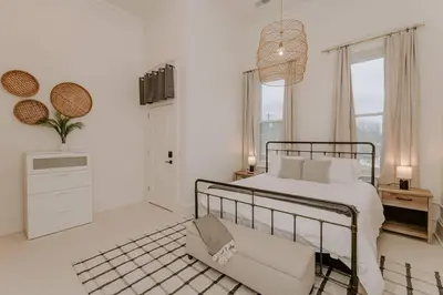 a white bedroom with a bed and a chair at East Main Lofts - Minimalist 302 in Madison