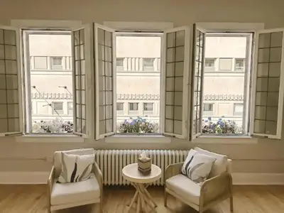 a living room with two chairs and a table and windows at The Historic Lyric Presidential Suite in Cincinnati