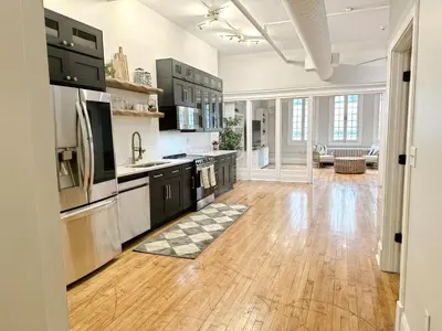 a large kitchen with black cabinets and a hard wood floor at The Historic Lyric Presidential Suite in Cincinnati