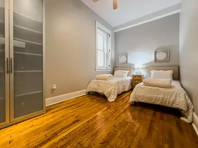 two beds in a room with wood floors and a window at The Historic Lyric Presidential Suite in Cincinnati