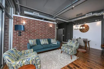 a living room with a couch and chairs and a brick wall at Luxury Condo in Akron Northside District in Akron