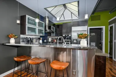 a kitchen with a counter with stools and a sink at Luxury Condo in Akron Northside District in Akron