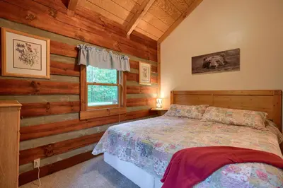 a bedroom with a bed with wooden walls and a window at Chickasaw in Logan