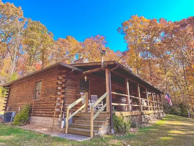a log cabin in the woods with a flag at Dewdrop Inn in Logan
