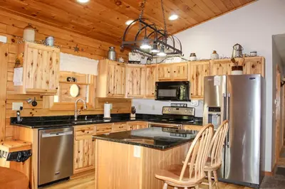 a kitchen with wooden cabinets and a stainless steel refrigerator at Dewdrop Inn in Logan