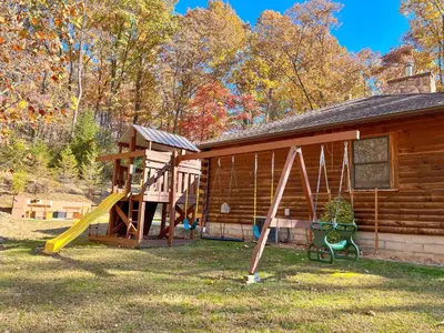 a playground in front of a log cabin at Dewdrop Inn in Logan