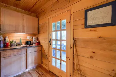 a kitchen with wooden walls and a large window at Bison Hollow Hideaway in South Bloomingville