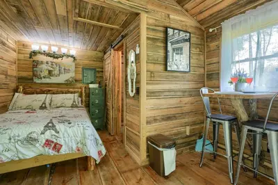 a bedroom with wooden walls and a bed and a table at Cypres Caban in Logan