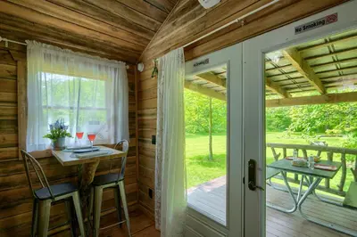 a door leading to a porch with a table and chairs at Cypres Caban in Logan