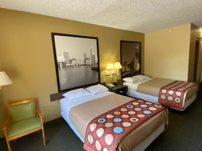 a hotel room with two beds and a chair at Super 8 by Wyndham Port Clinton in Port Clinton
