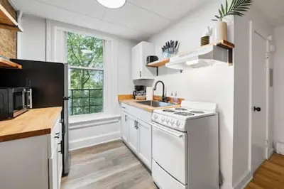 a white kitchen with a sink and a stove at Comfy 1BR with Parking - Near UC, Zoo, Downtown in Cincinnati