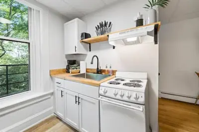 a white kitchen with a stove and a sink at Comfy 1BR with Parking - Near UC, Zoo, Downtown in Cincinnati