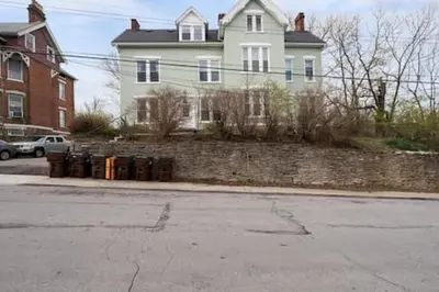 a large white house with a brick wall at Comfy 1BR with Parking - Near UC, Zoo, Downtown in Cincinnati