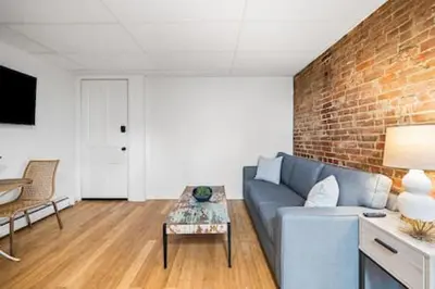 a living room with a blue couch and a brick wall at Comfy 1BR with Parking - Near UC, Zoo, Downtown in Cincinnati