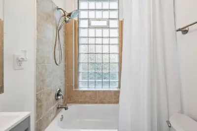 a bathroom with a tub and a shower with a window at Comfy 1BR with Parking - Near UC, Zoo, Downtown in Cincinnati