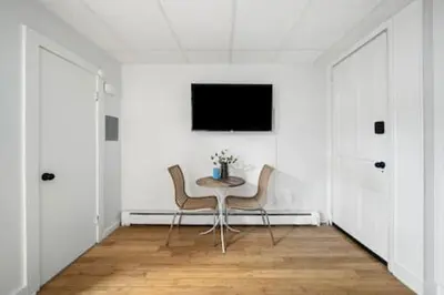 a table and chairs in a white room with a tv at Comfy 1BR with Parking - Near UC, Zoo, Downtown in Cincinnati