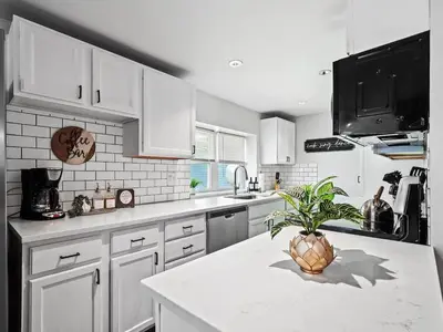 a kitchen with white cabinets and a plant on a counter at Family Fun: Comfy Home, 10 Min to Cedar Point Fun! in Huron
