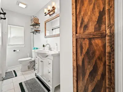 a bathroom with a wooden door with a sink and a toilet at Family Fun: Comfy Home, 10 Min to Cedar Point Fun! in Huron