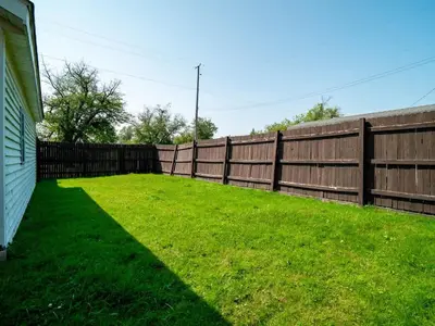 a backyard with a fence and green grass at Family Fun: Comfy Home, 10 Min to Cedar Point Fun! in Huron