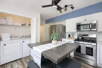 a kitchen with white cabinets and a table with a potted plant at Port Clinton Getaway Near the Beach in Port Clinton