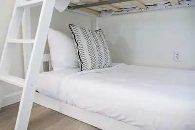 a white bunk bed with white pillows and a ladder at Port Clinton Getaway Near the Beach in Port Clinton