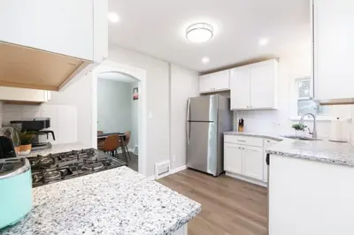 a kitchen with white cabinets and a stainless steel refrigerator at Modern 3BR home next to park, office space, & more in University Heights