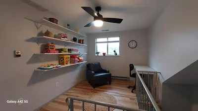 a room with a staircase with a chair and a ceiling fan at The Meeker House (Charming 3/4 Bedroom Home) in Bowling Green