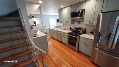 a kitchen with stainless steel appliances and wooden floors at The Meeker House (Charming 3/4 Bedroom Home) in Bowling Green